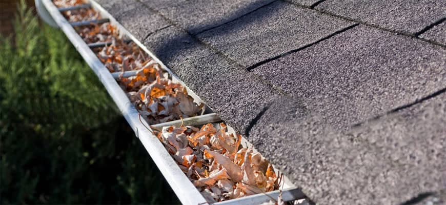 Gutter service at the eaves — residential roofline and stucco, East Valley