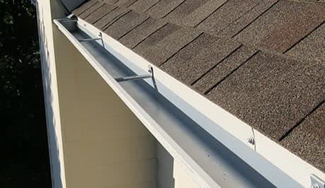 Gutter trough and downspout detail during a cleaning visit — residential exterior