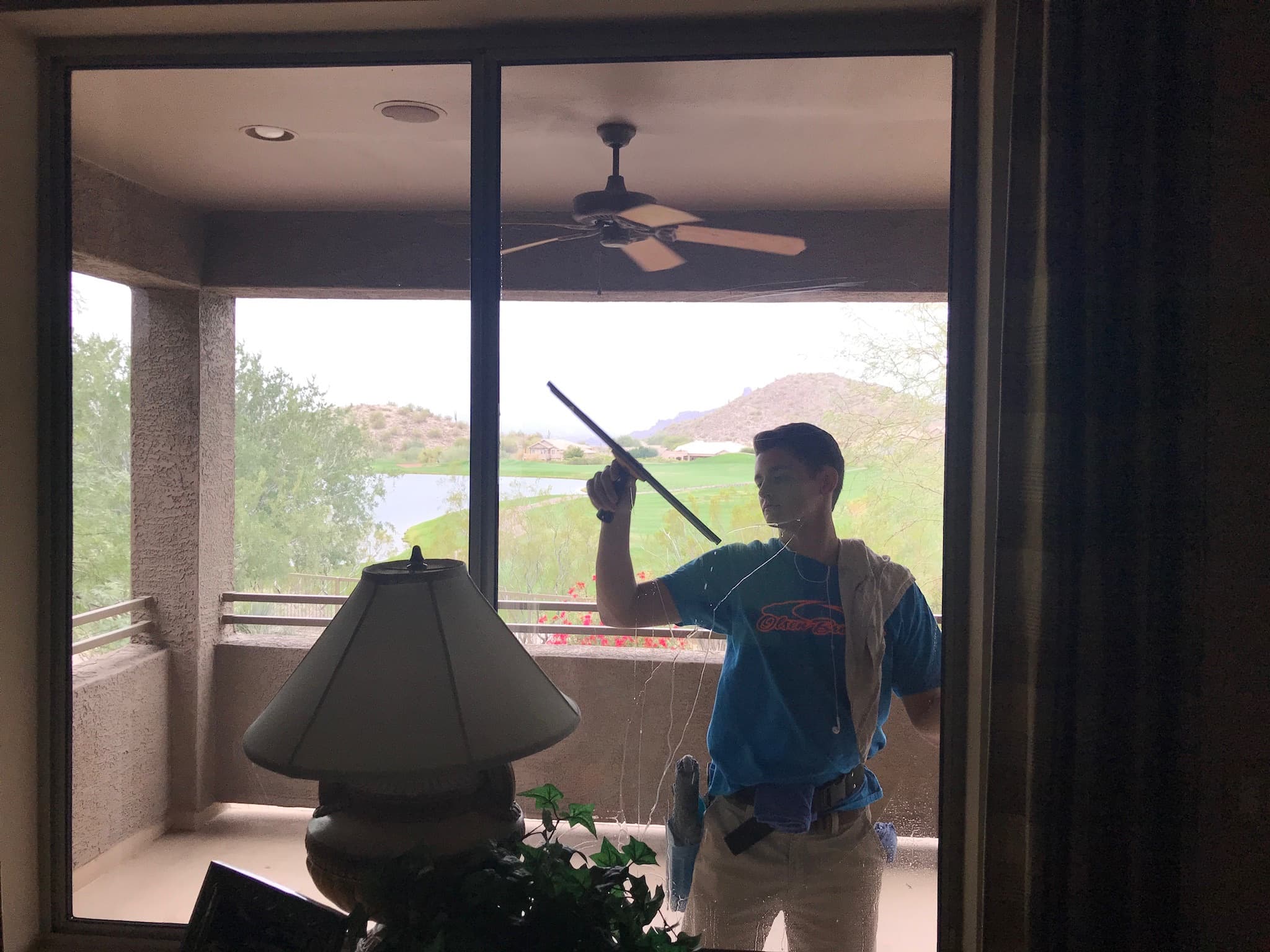 An Olsen Brothers window cleaner squeegeeing a large balcony window at an East Valley home