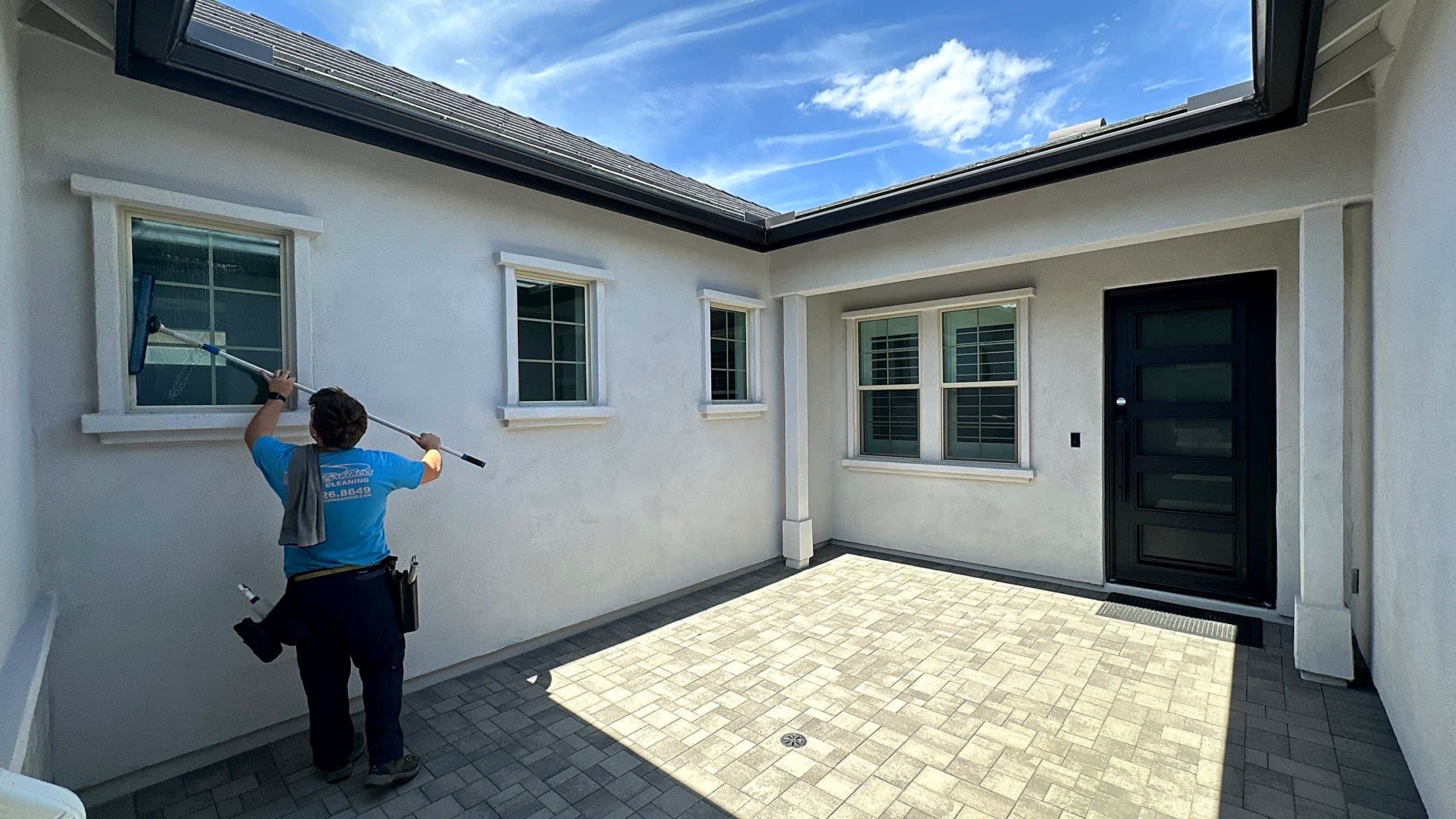 Olsen Brothers technician cleaning exterior windows with a water-fed pole at a Queen Creek home