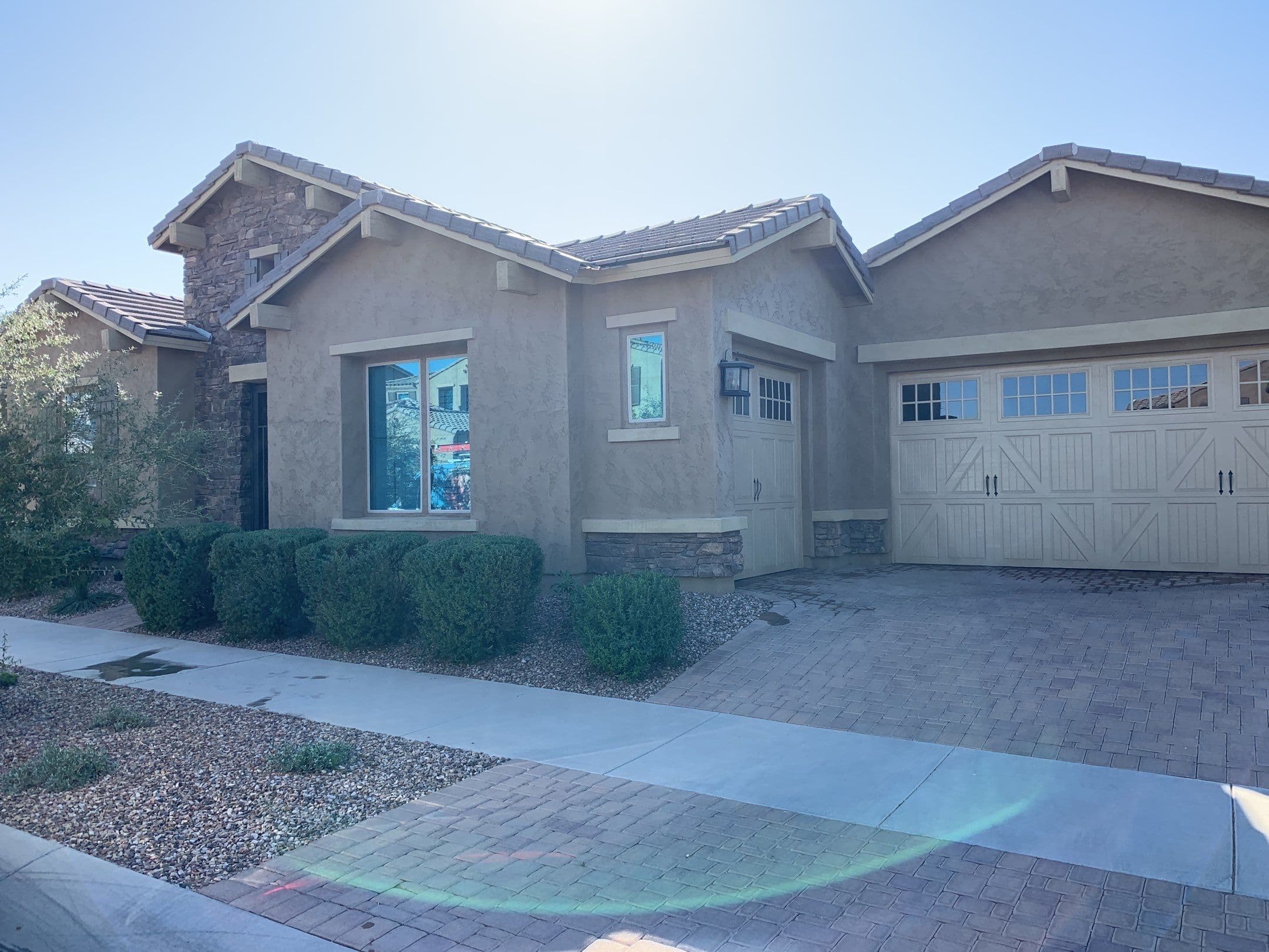 Eastmark-area home with clean front windows, stone accents, and carriage-style garage doors — Mesa, Arizona