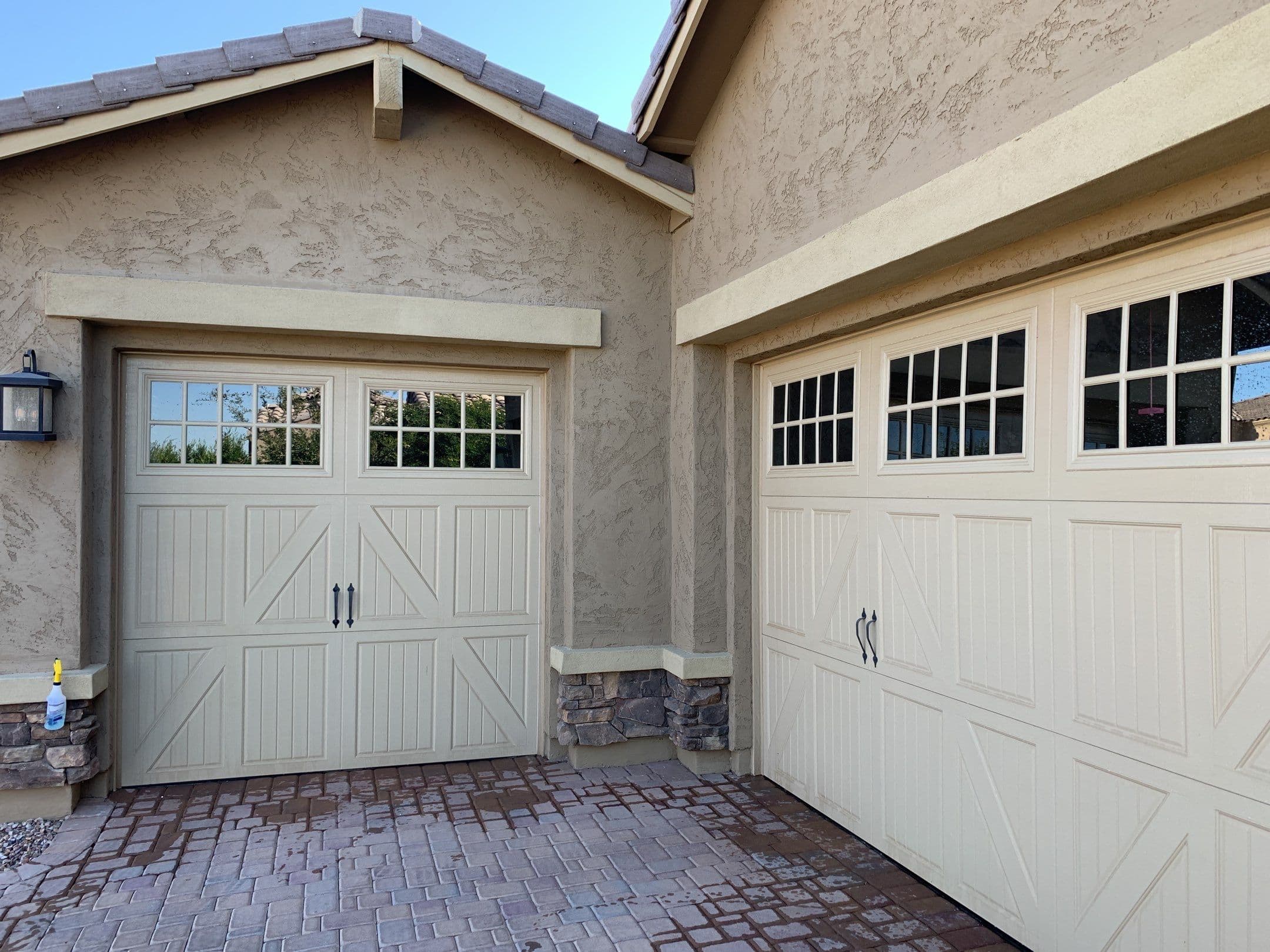 Carriage-style garage doors with clear window panes and washed paver driveway — Eastmark area