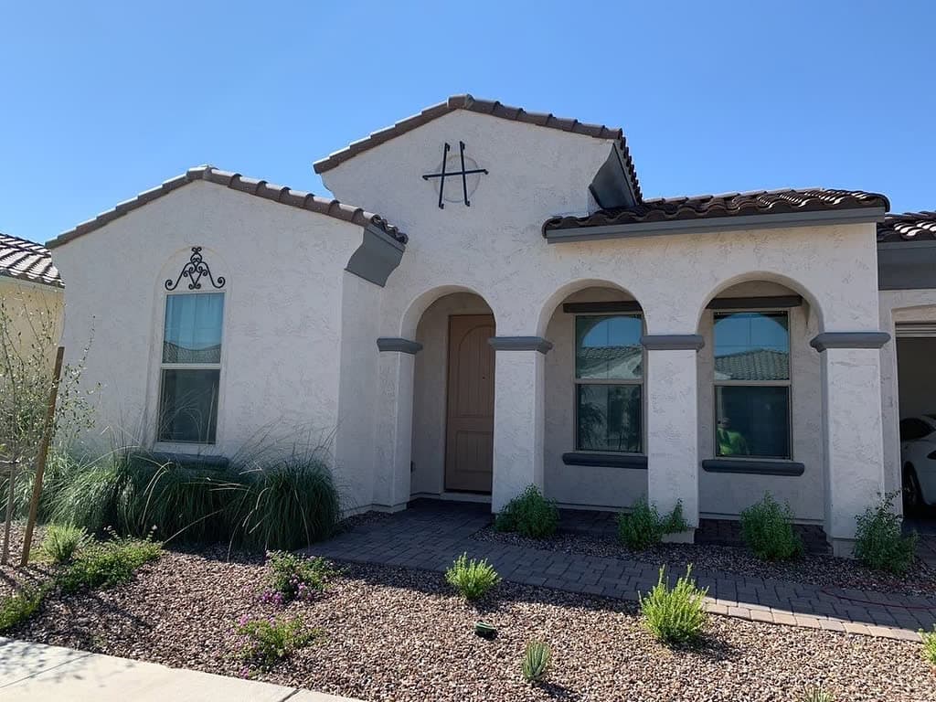 Front elevation with arched windows reflecting blue sky — Southwest-style home after window cleaning, Eastmark area