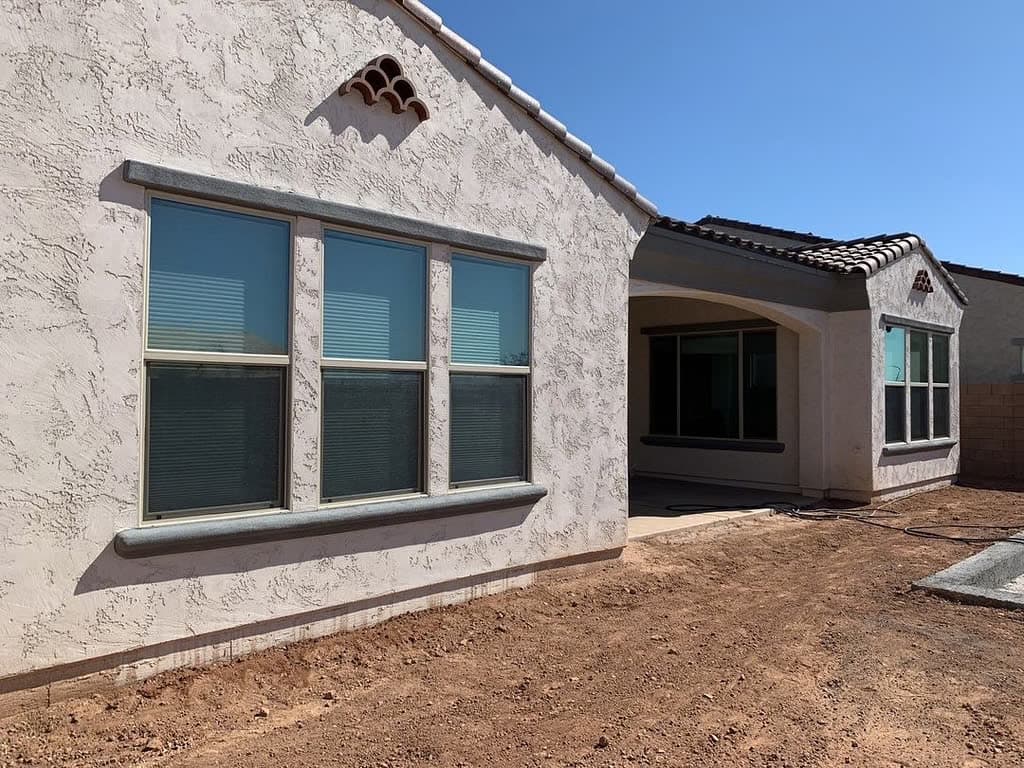 Side and rear stucco elevations with large dark-trimmed windows — Eastmark-area residential job