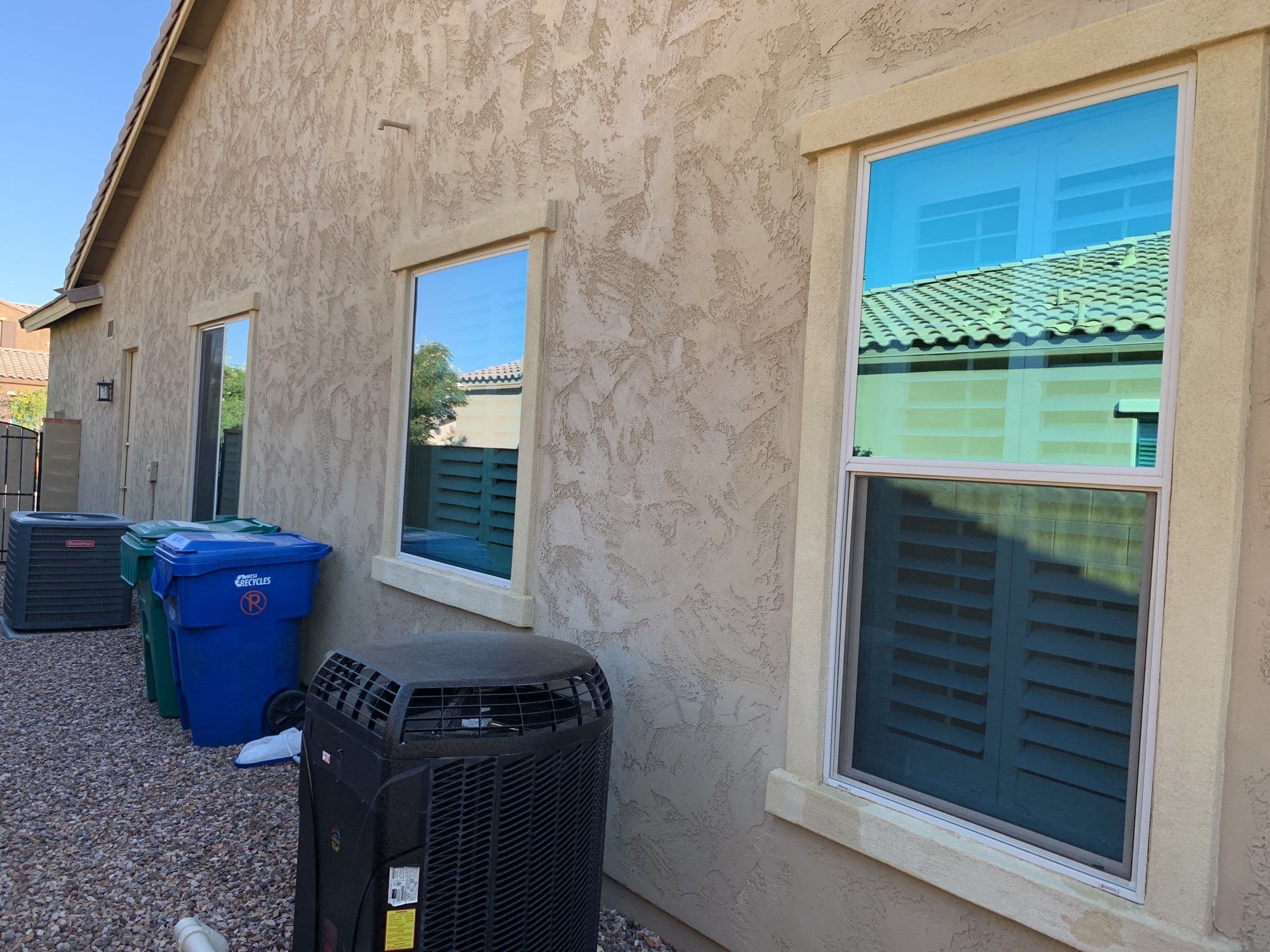 Side yard with gravel, HVAC pads, and clean reflective windows — Eastmark home